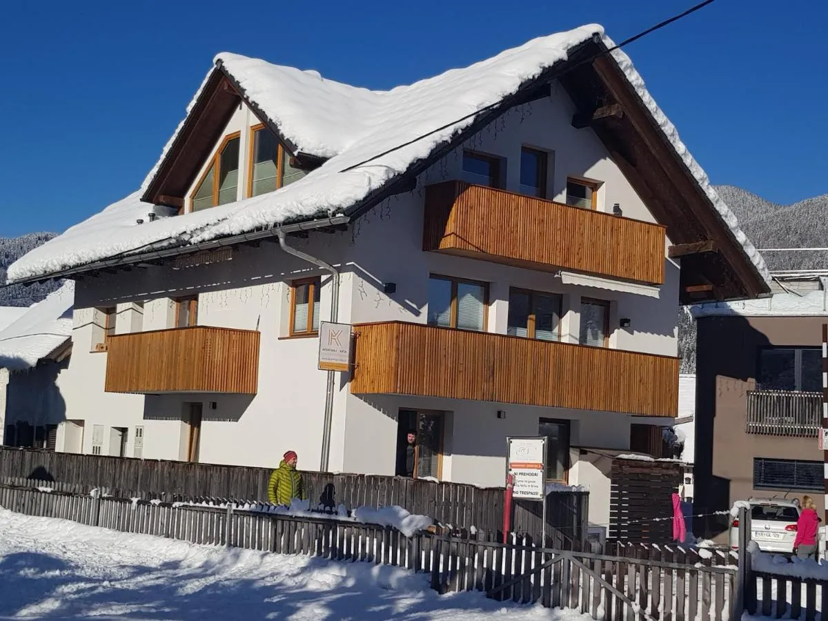 Hiša Apartmaji Katja pozimi, z lesenima balkonoma v dveh nadstropjih